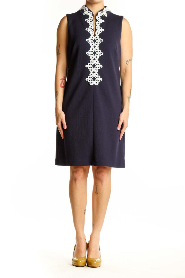 Navy sleeveless shift dress with white lace trim down center front, worn by model showing elegant A-line silhouette