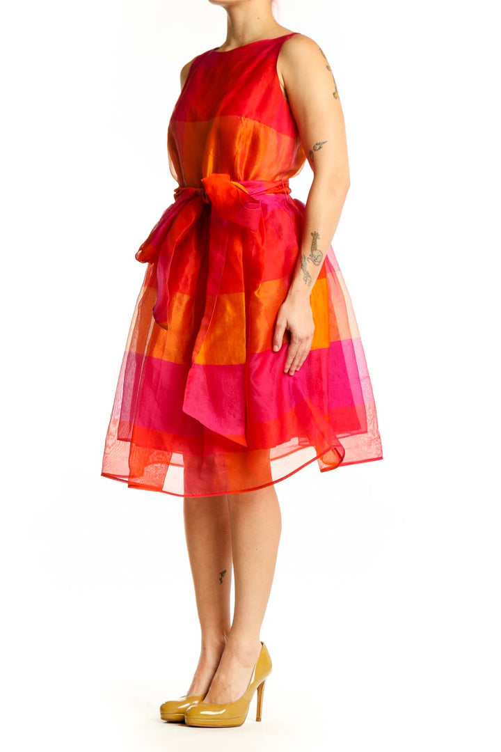 Front view of red and orange colorblock midi dress with tie-waist belt and sheer overlay skirt