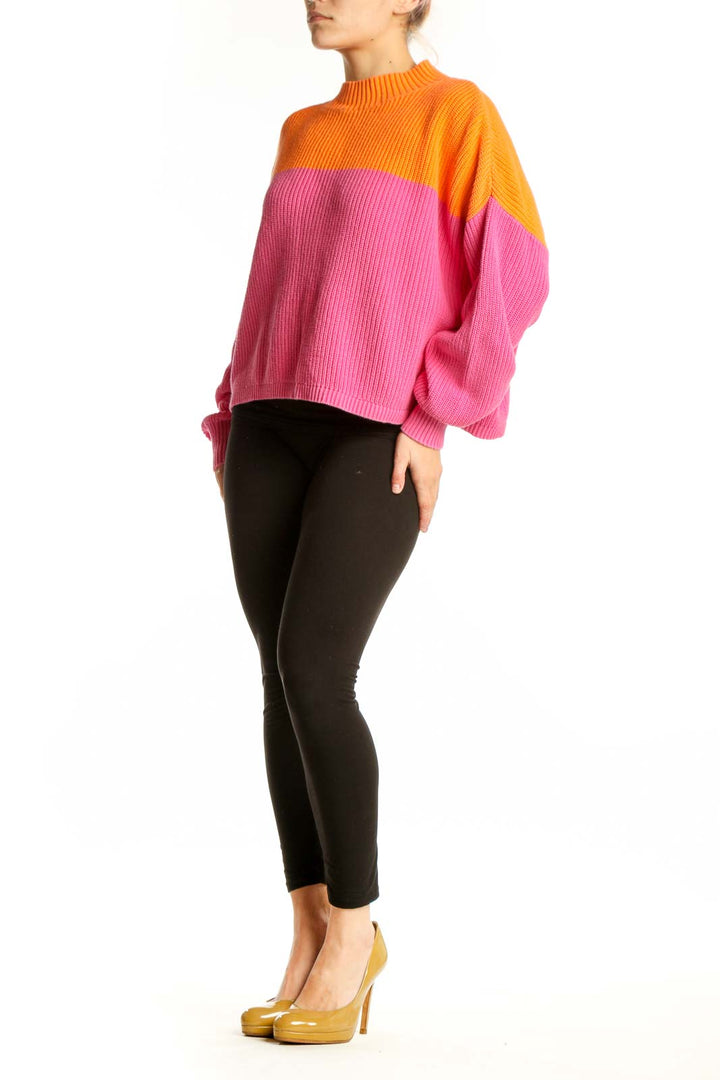 Orange and pink color block knit pullover with crew neckline and long sleeves, front view