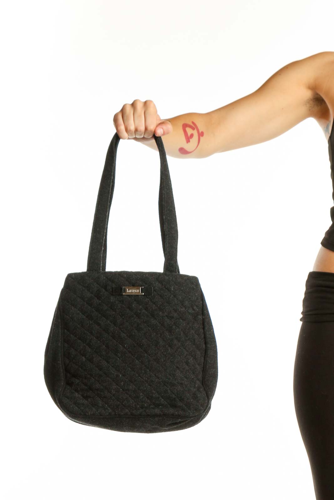 Black quilted wool shoulder bag by Christian Lauren with dual straps, held by model against white background
