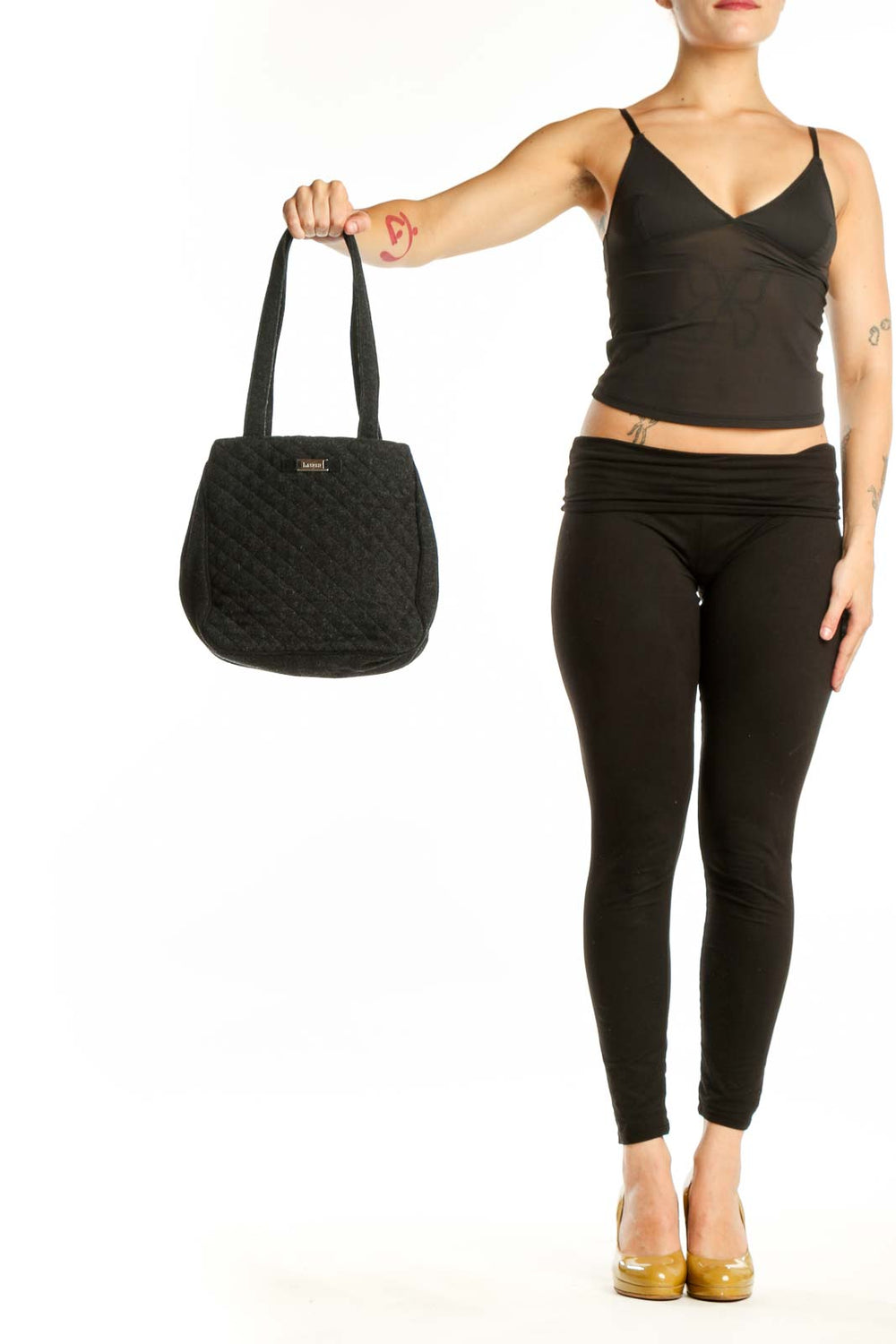 Black quilted wool shoulder bag by Christian Lauren with dual straps, held by model against white background