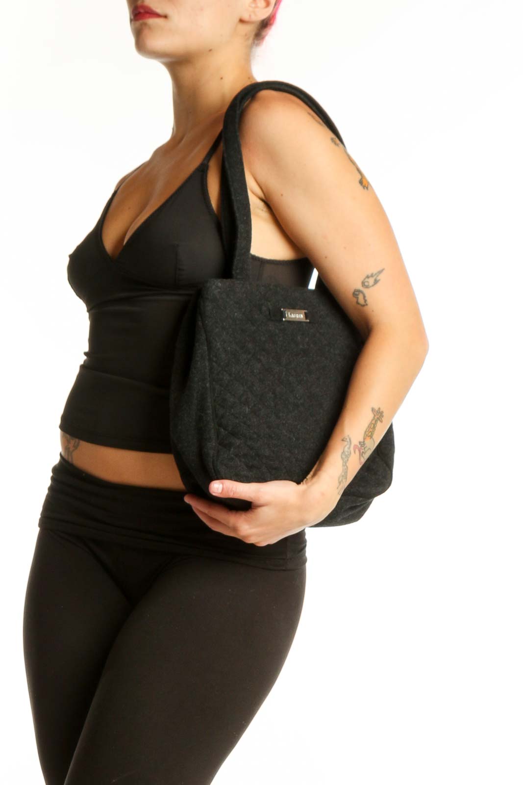 Black quilted wool shoulder bag by Christian Lauren with dual straps, held by model against white background