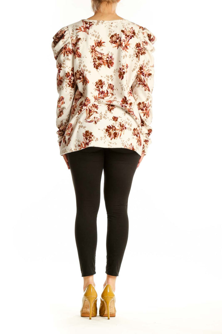 Cream floral blouse with puff sleeves, back view on model wearing black leggings