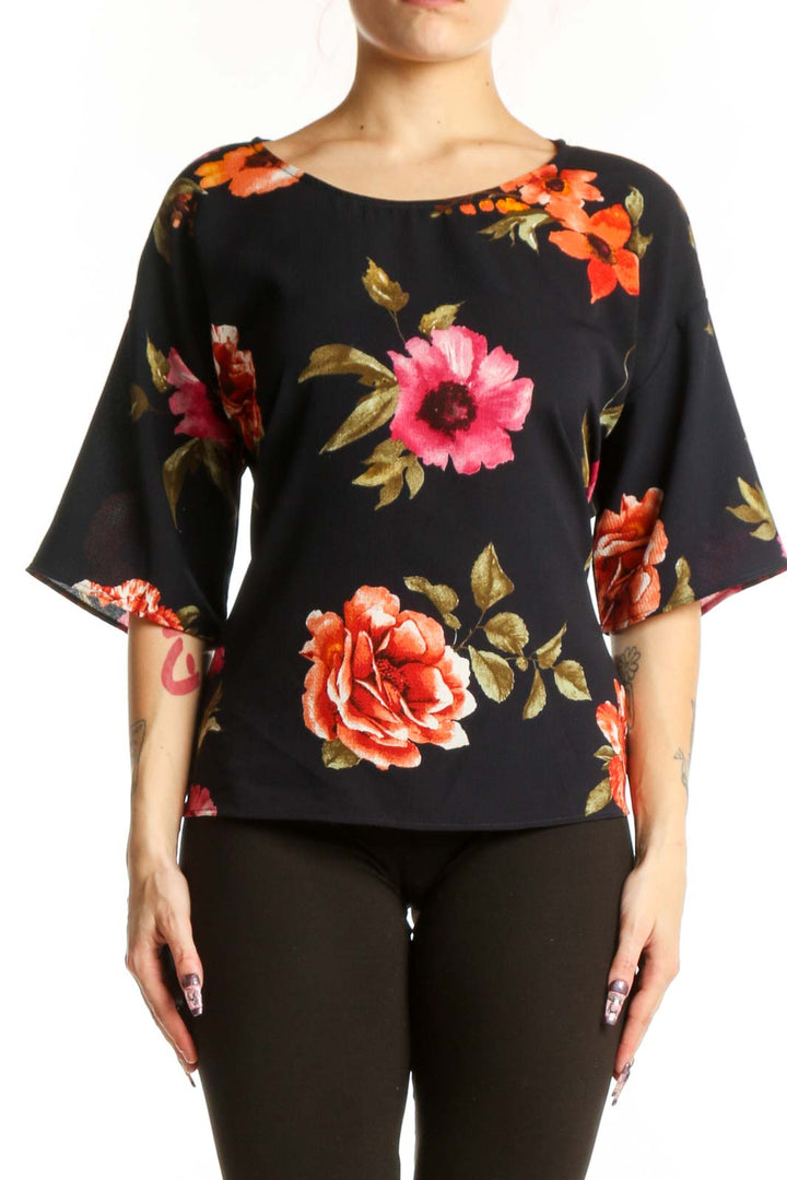 Black floral half sleeve top with vibrant red, pink, and orange roses and golden leaves, front view on model