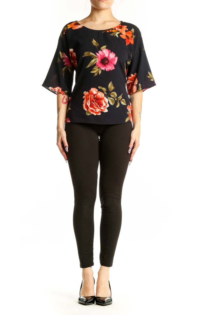Black floral half sleeve top with vibrant red, pink, and orange roses and golden leaves, front view on model