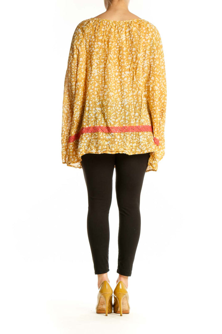 Yellow floral print cotton blouse with bell sleeves and coral trim detail, back view