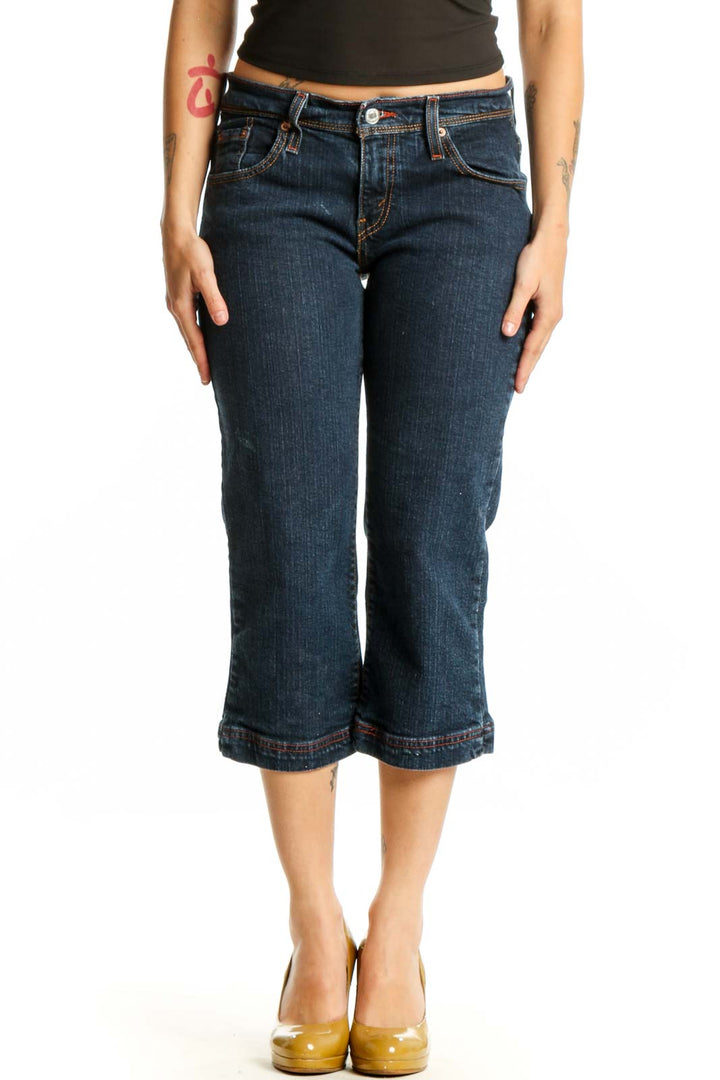Front view of dark blue Levi's cropped denim jeans with rolled hem, fitted waist and thigh, worn with black crop top