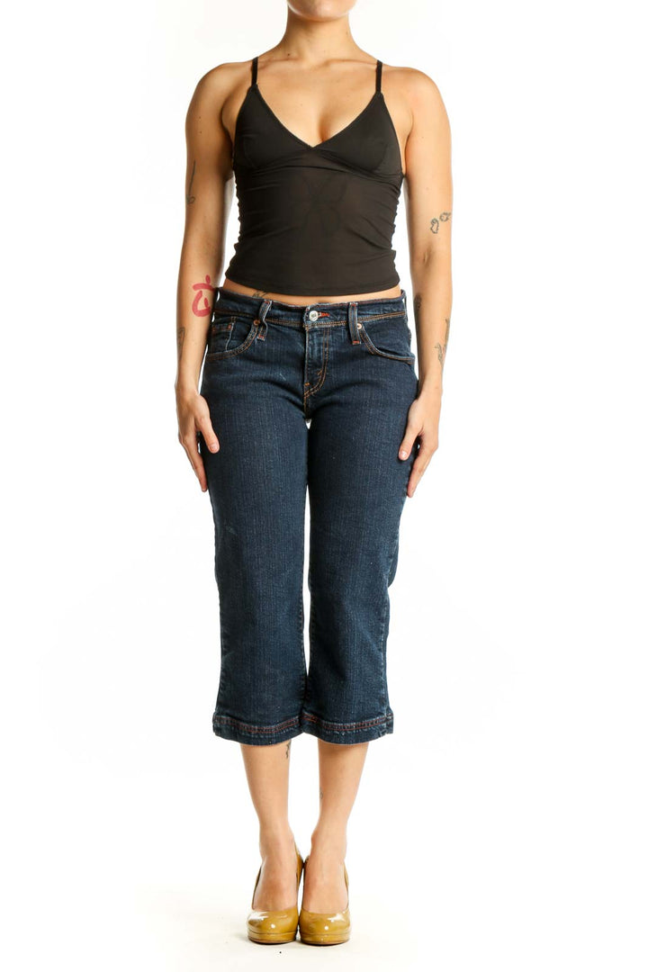 Front view of dark blue Levi's cropped denim jeans with rolled hem, fitted waist and thigh, worn with black crop top