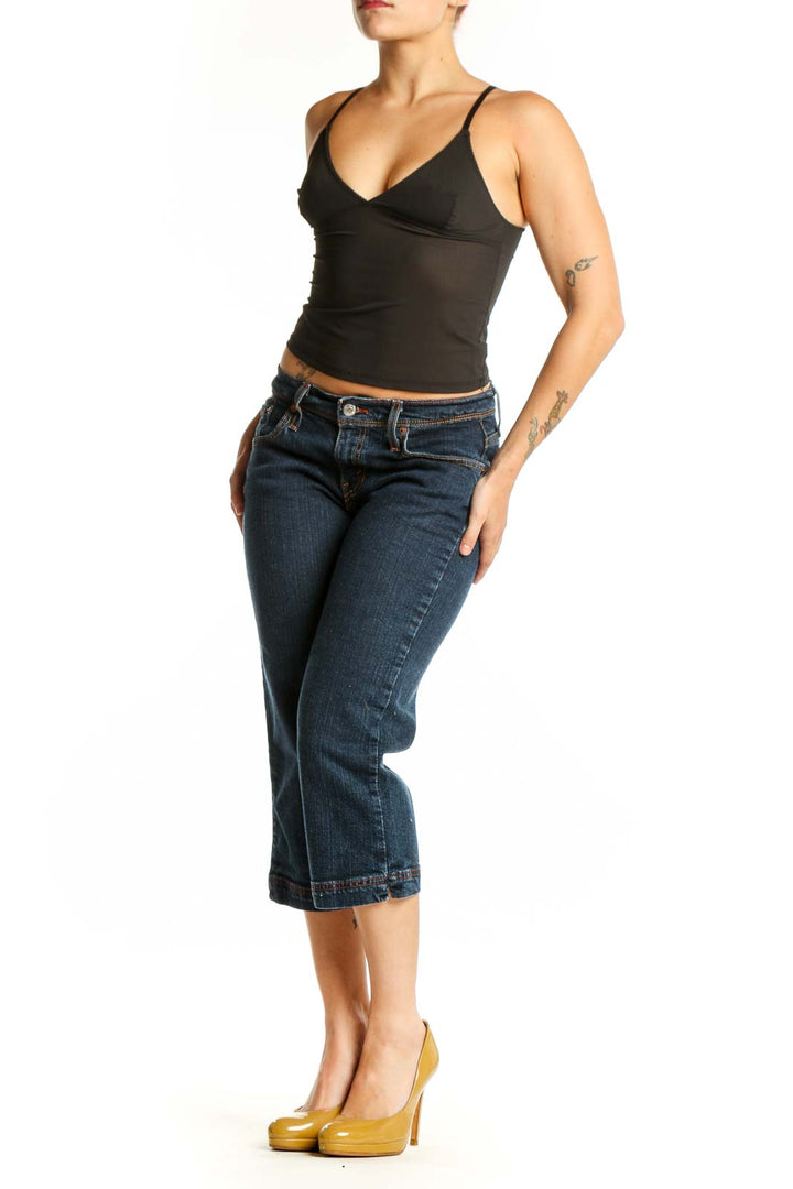 Front view of dark blue Levi's cropped denim jeans with rolled hem, fitted waist and thigh, worn with black crop top