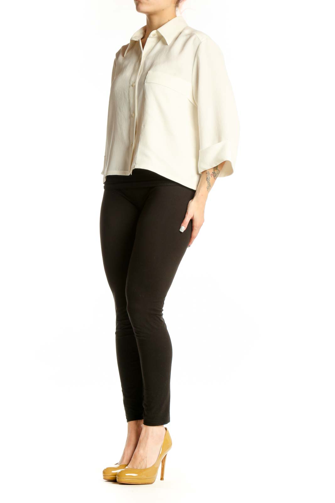 Woman wearing cream button-up collared blouse with three-quarter sleeves and chest pocket, paired with black pants