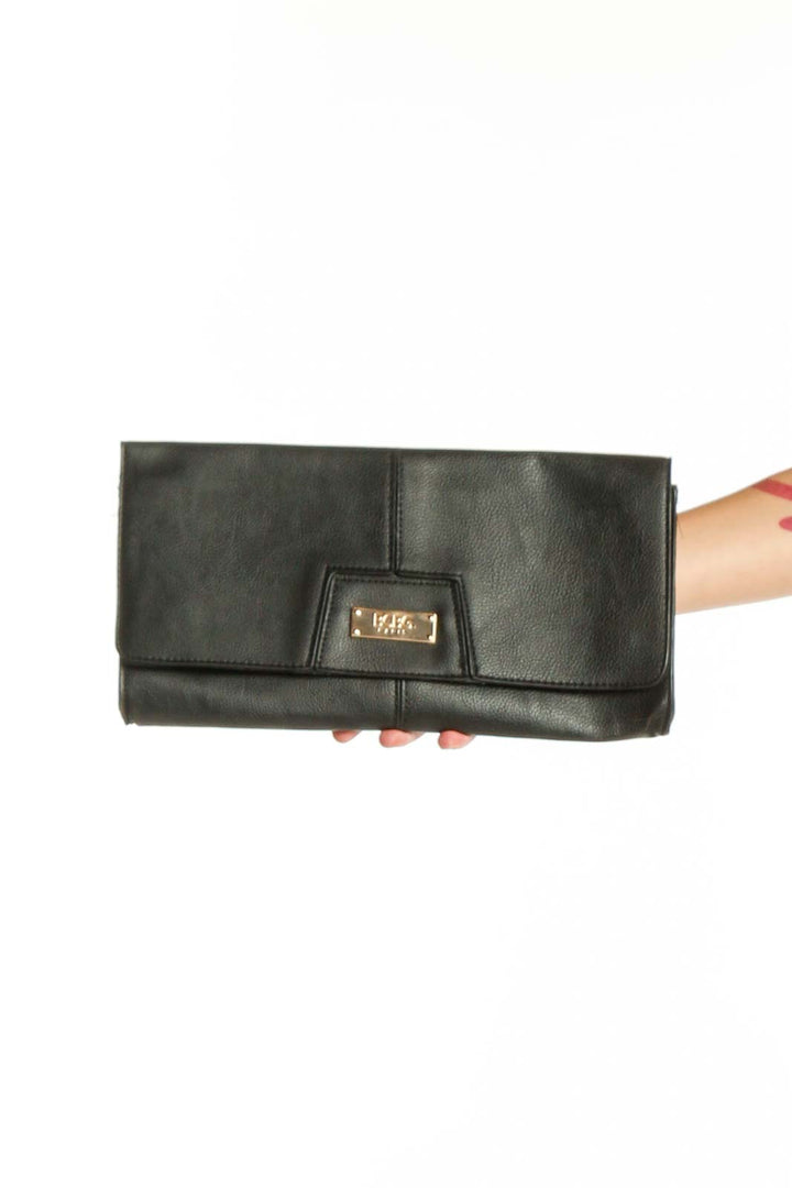 Black leather fold-over clutch with gold-tone hardware by BCBG Paris, held in hand