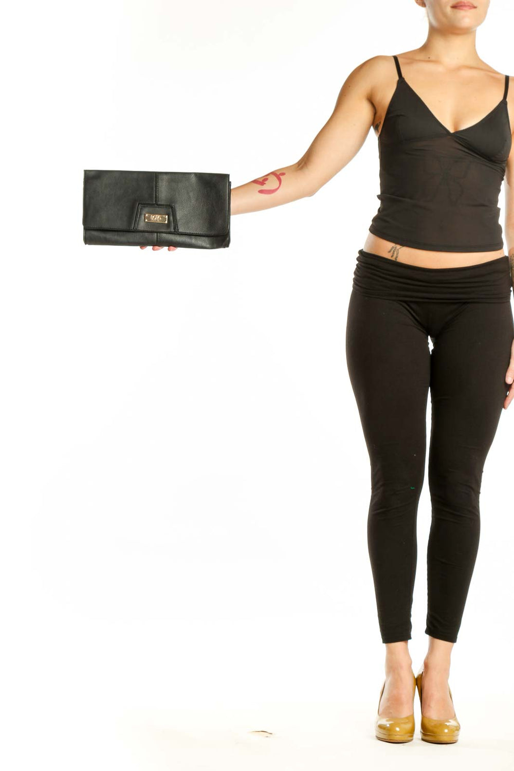 Black leather fold-over clutch with gold-tone hardware by BCBG Paris, held in hand