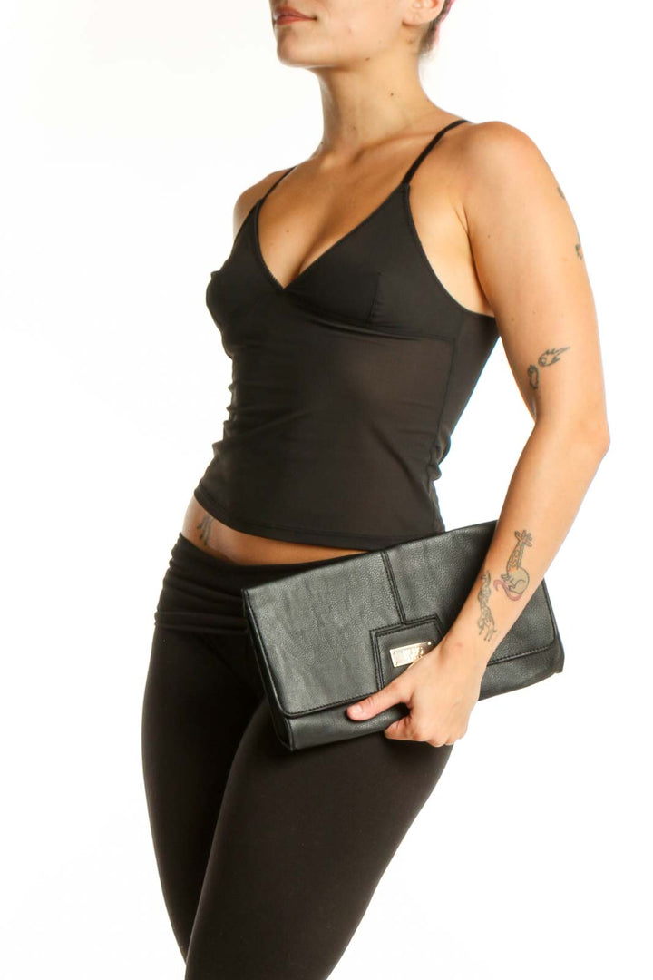 Black leather fold-over clutch with gold-tone hardware by BCBG Paris, held in hand