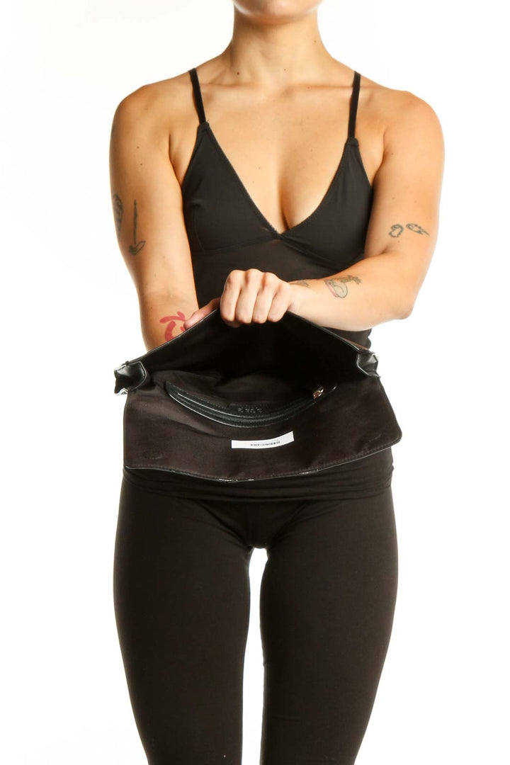 Black leather fold-over clutch styled with black outfit, showing back view and compact design