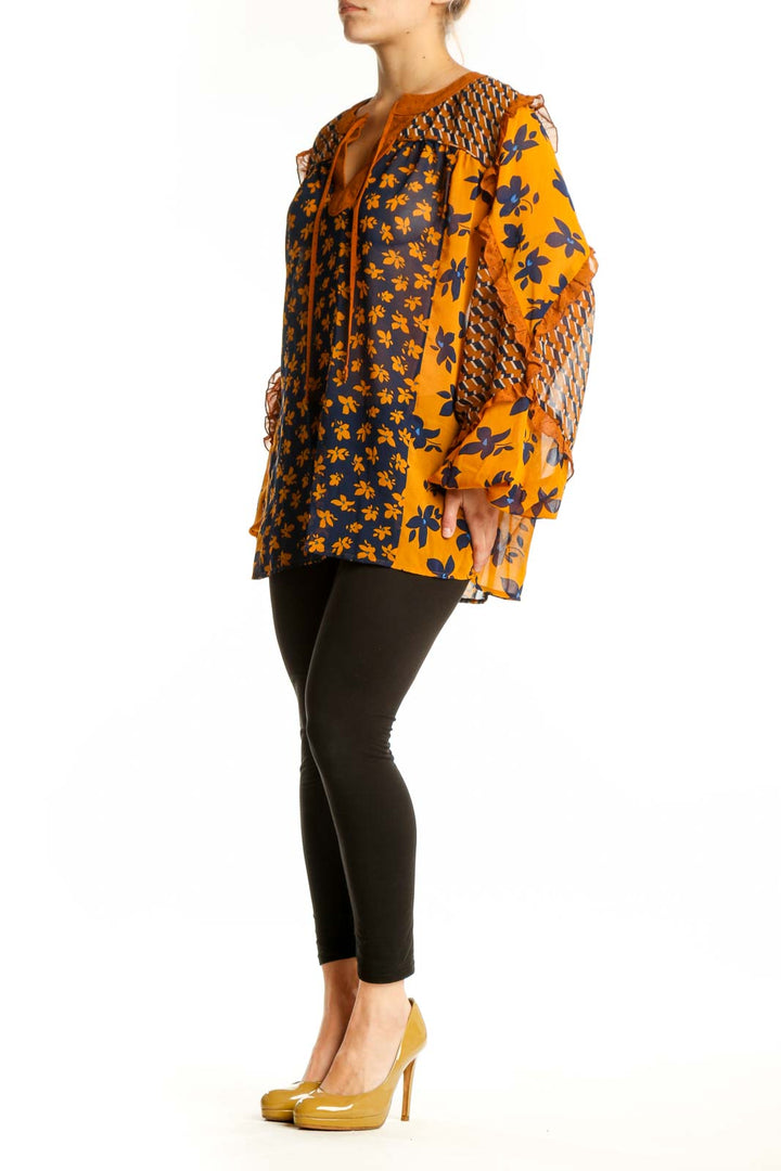 Navy and orange floral Cabi blouse with textured bell sleeves and tie neckline, front view on model