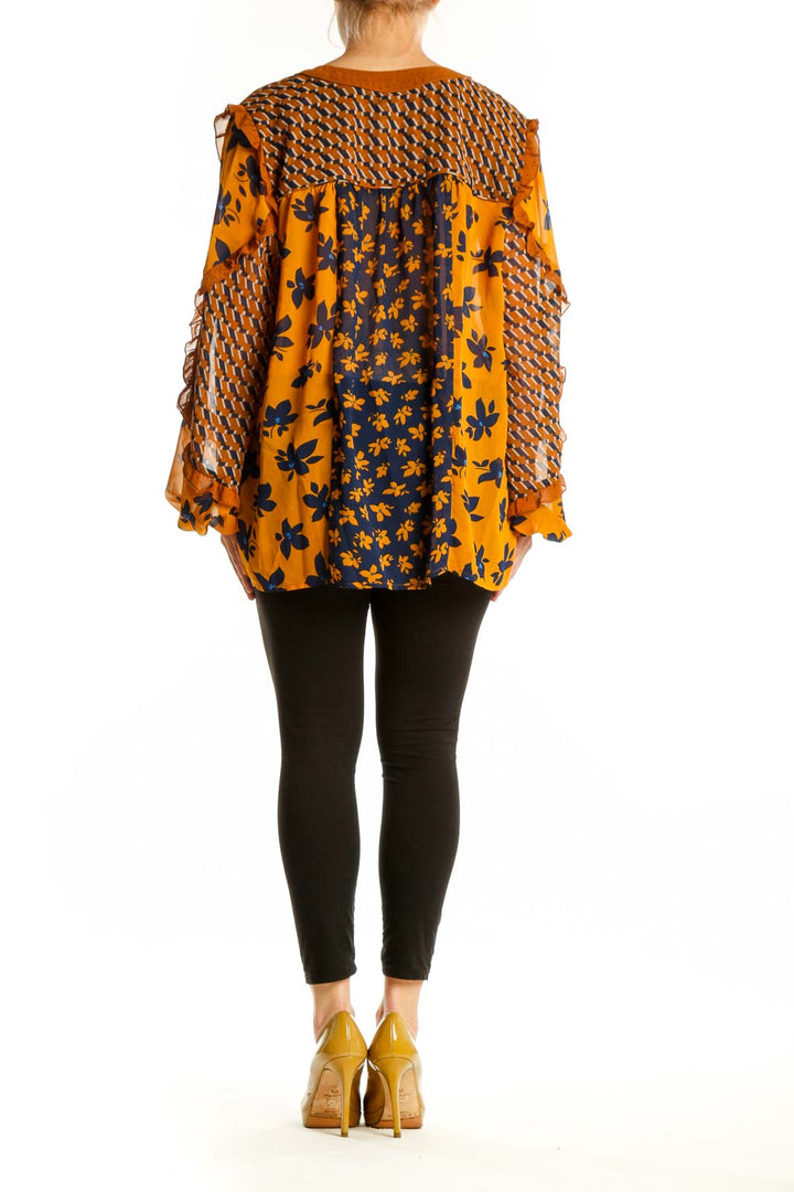 Navy and orange floral Cabi blouse with geometric patterned bell sleeves, back view on model