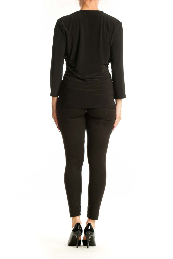 Black wrap long sleeve top with ruched sides and metallic accent, back view