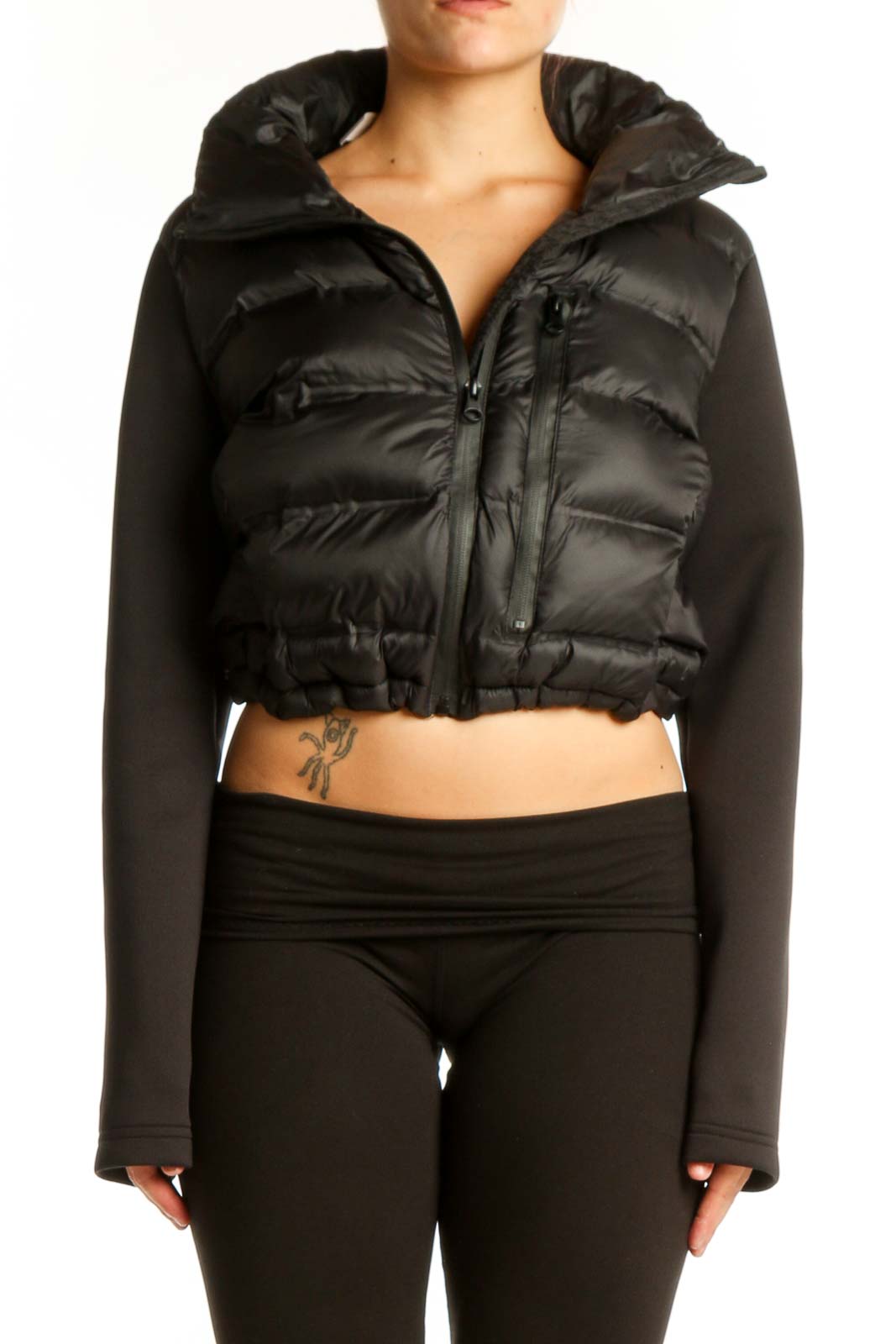 Black cropped puffer jacket with knit sleeves and quilted nylon front, worn with black pants