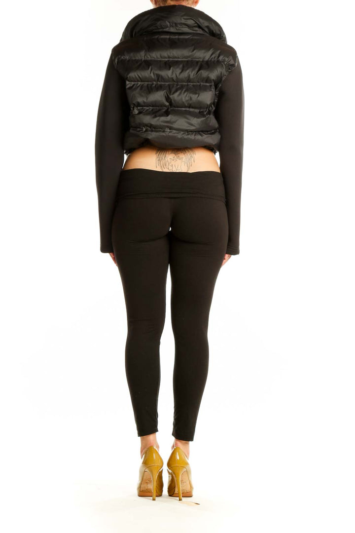 Back view of black cropped puffer jacket showing quilted puffer design and knit sleeve details