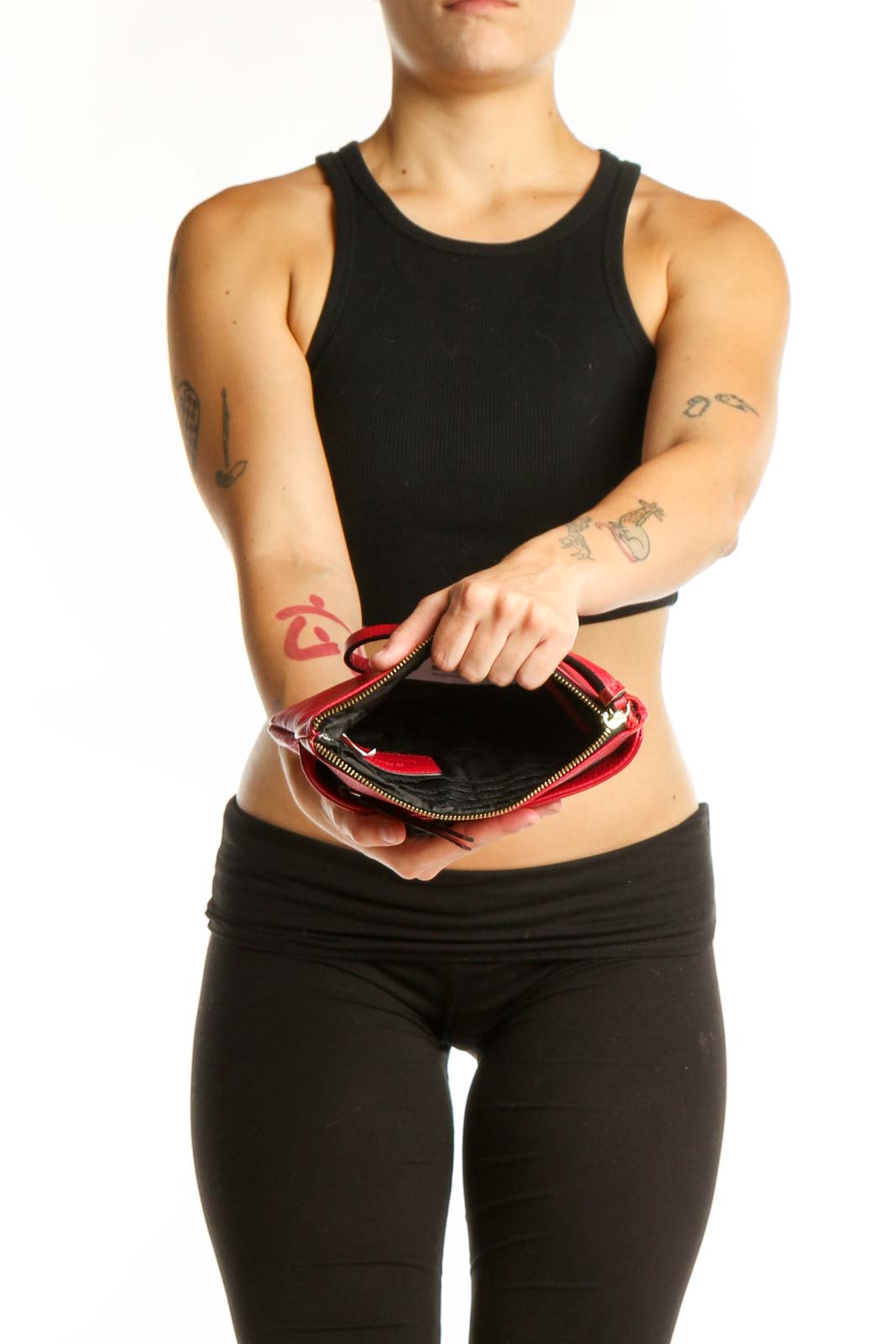 Red leather pleated clutch wristlet styled with black outfit, showing side profile and wristlet strap