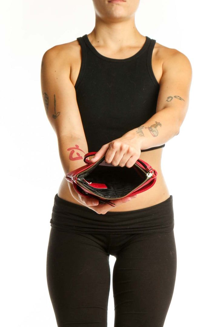 Red leather pleated clutch wristlet styled with black outfit, showing side profile and wristlet strap