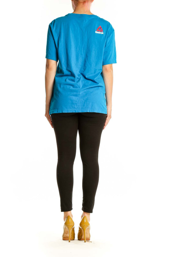 Blue Reebok graphic t-shirt back view showing distressed graphic design, worn with black leggings
