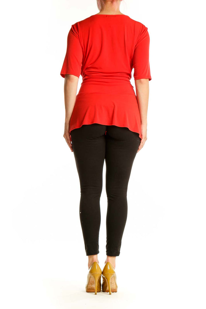 Red wrap blouse with tie waist detail, back view on model wearing black pants
