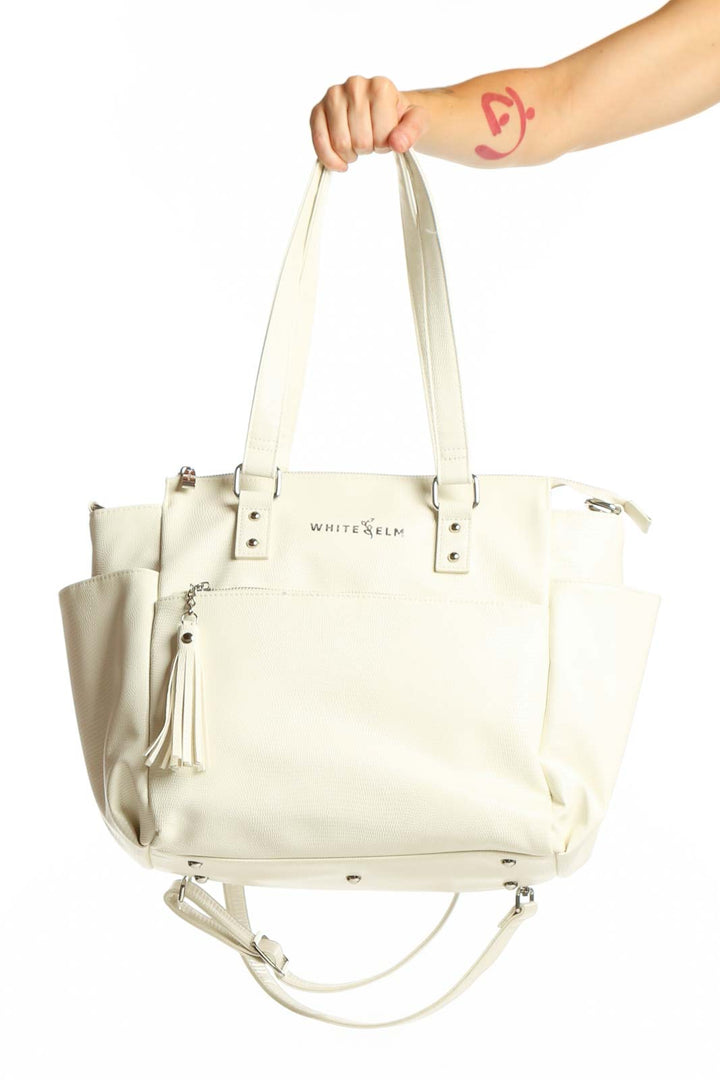 WHITE ELM cream leather tote bag with dual handles and tassel accent, front view