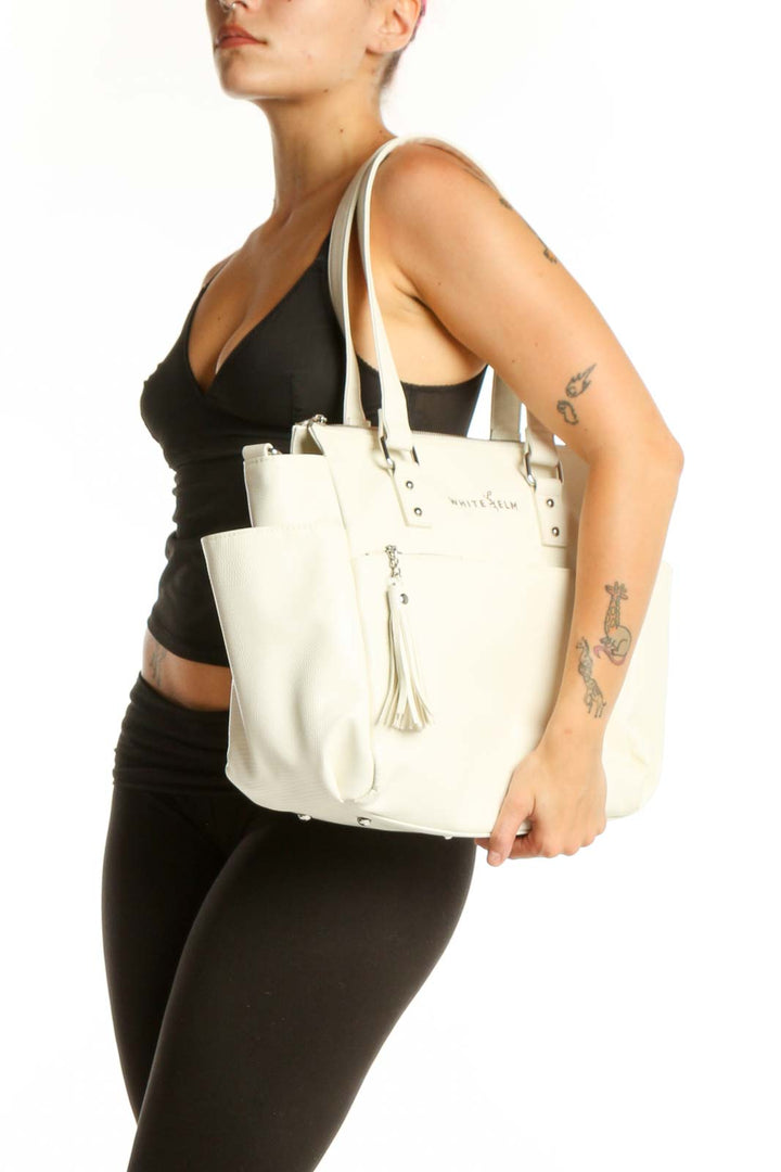 WHITE ELM cream leather tote bag with dual handles and tassel accent, front view