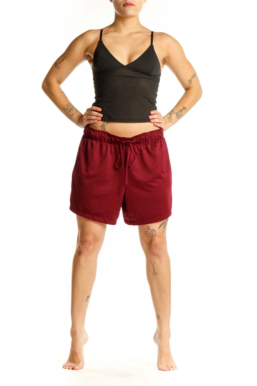 Front view of burgundy Nike athletic shorts with elastic waistband and drawstring closure, paired with black crop top