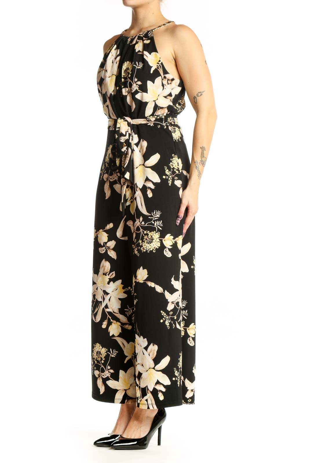 Black floral halter jumpsuit with cream and gold botanical print, adjustable tie waist, and wide-leg silhouette, front view