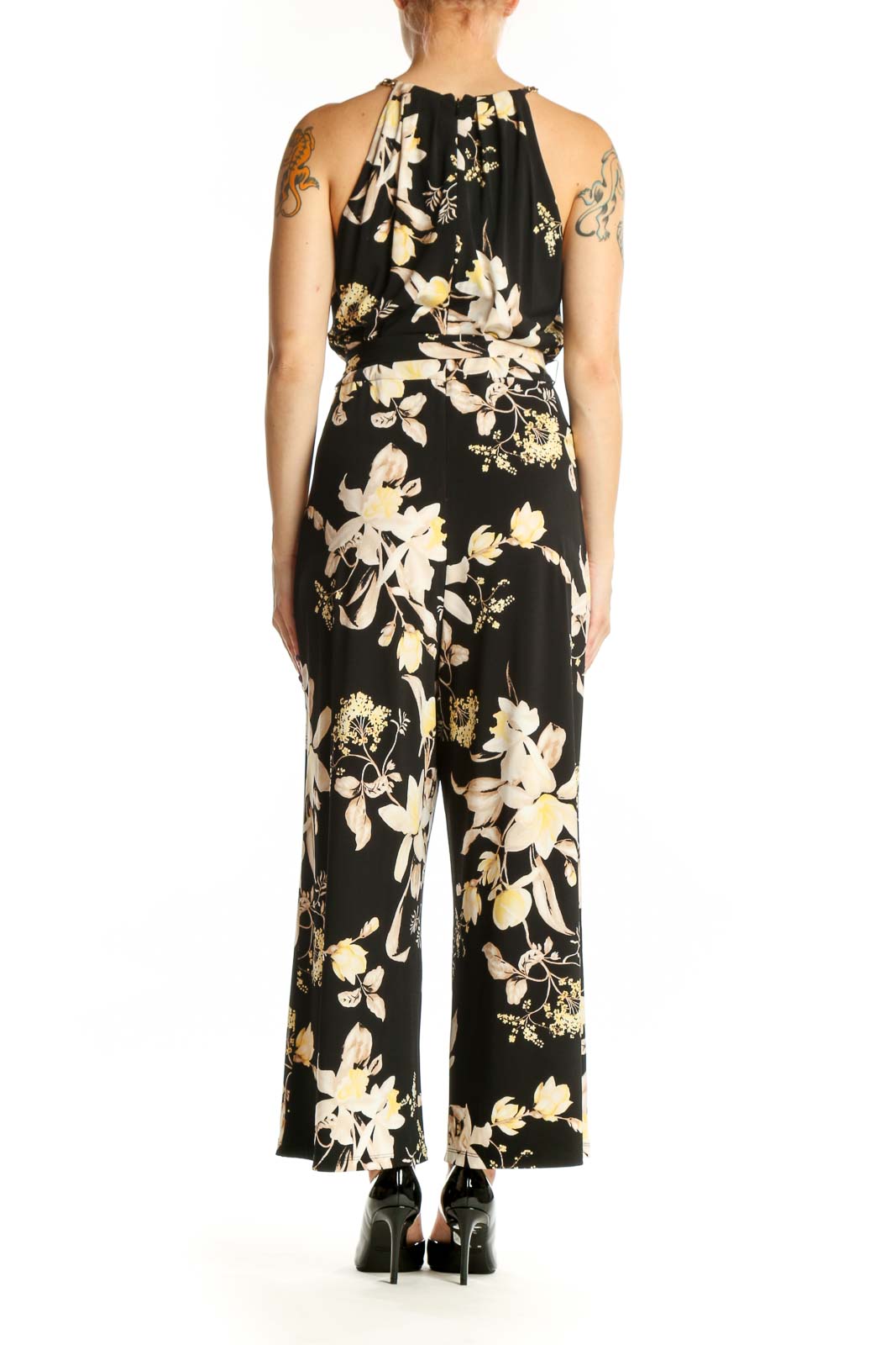 Black floral halter jumpsuit with cream and gold botanical print, adjustable tie waist, and wide-leg silhouette, back view