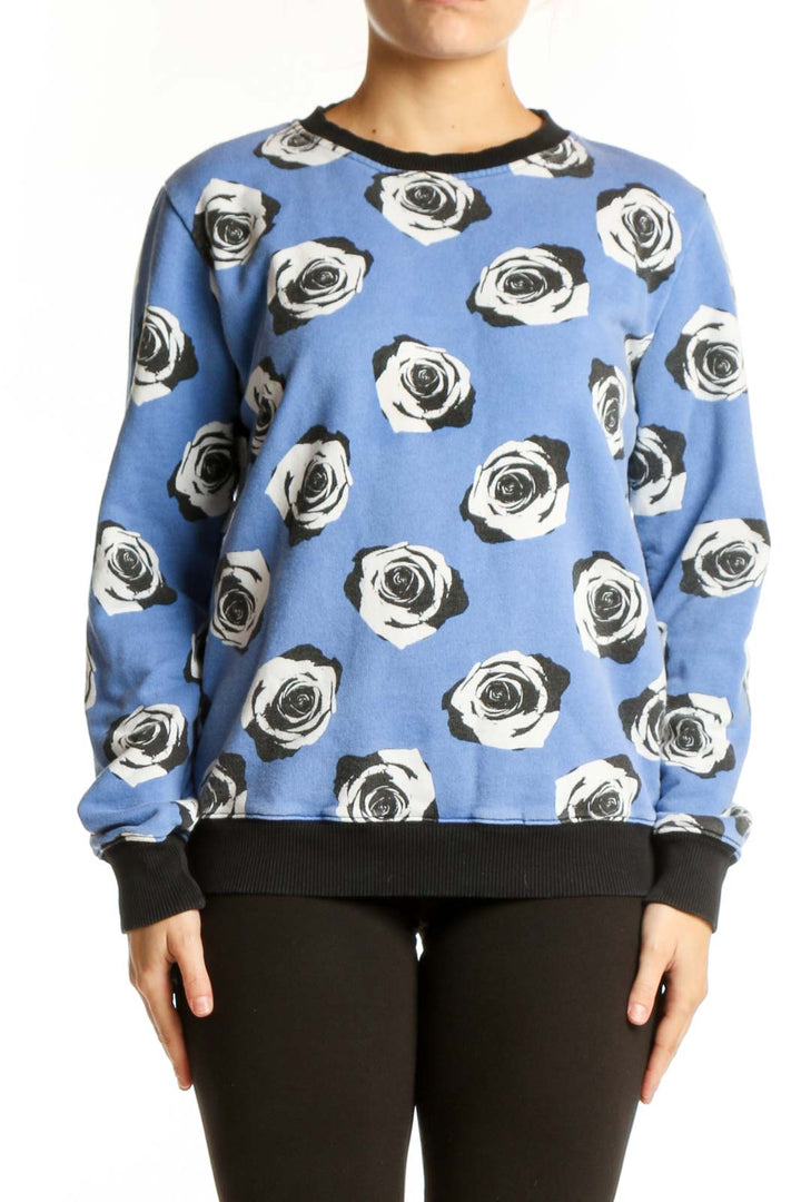 Blue cotton sweatshirt with black and white rose print and black ribbed crew neckline, front view