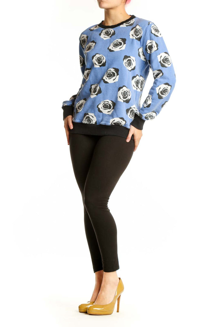 Blue cotton sweatshirt with black and white rose print and black ribbed crew neckline, front view
