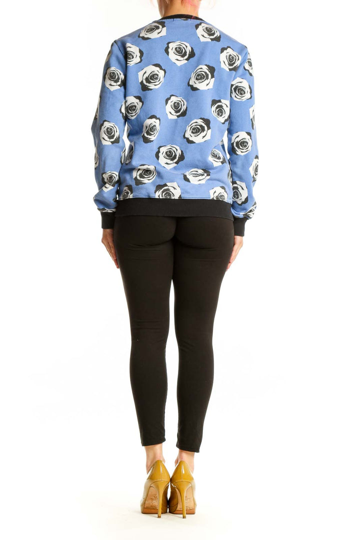 Blue cotton sweatshirt with black and white rose print and black ribbed cuffs, back view