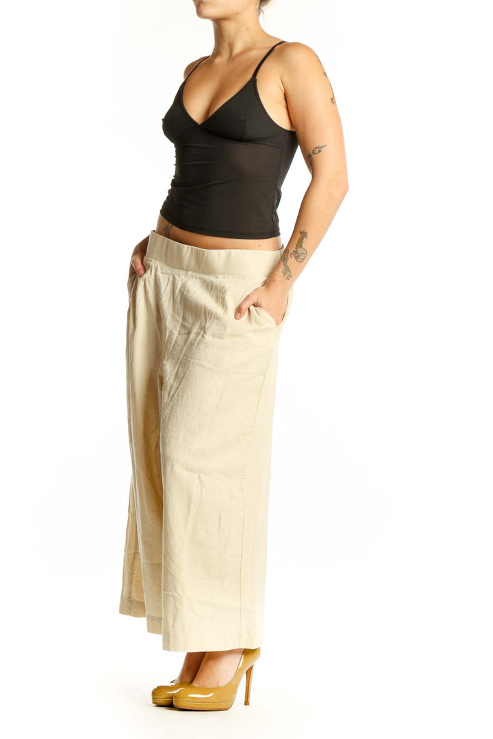Front view of cream linen wide-leg cropped pants with elastic waistband and side pockets