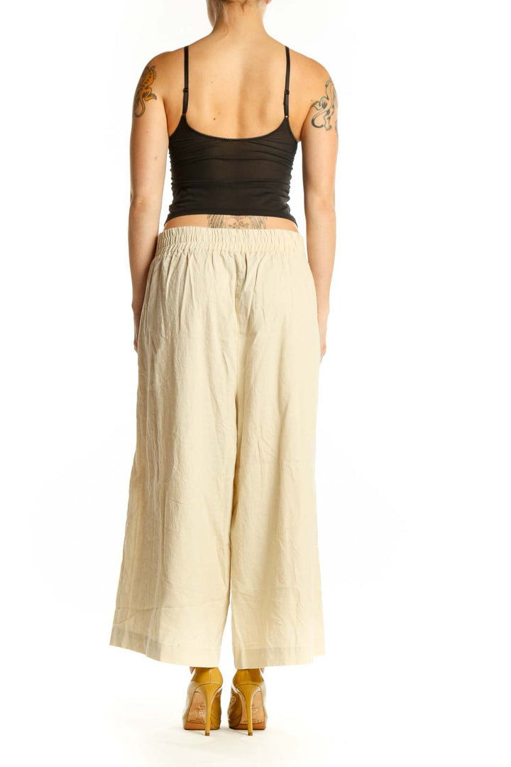 Back view of cream linen wide-leg cropped pants showing relaxed fit and functional pockets