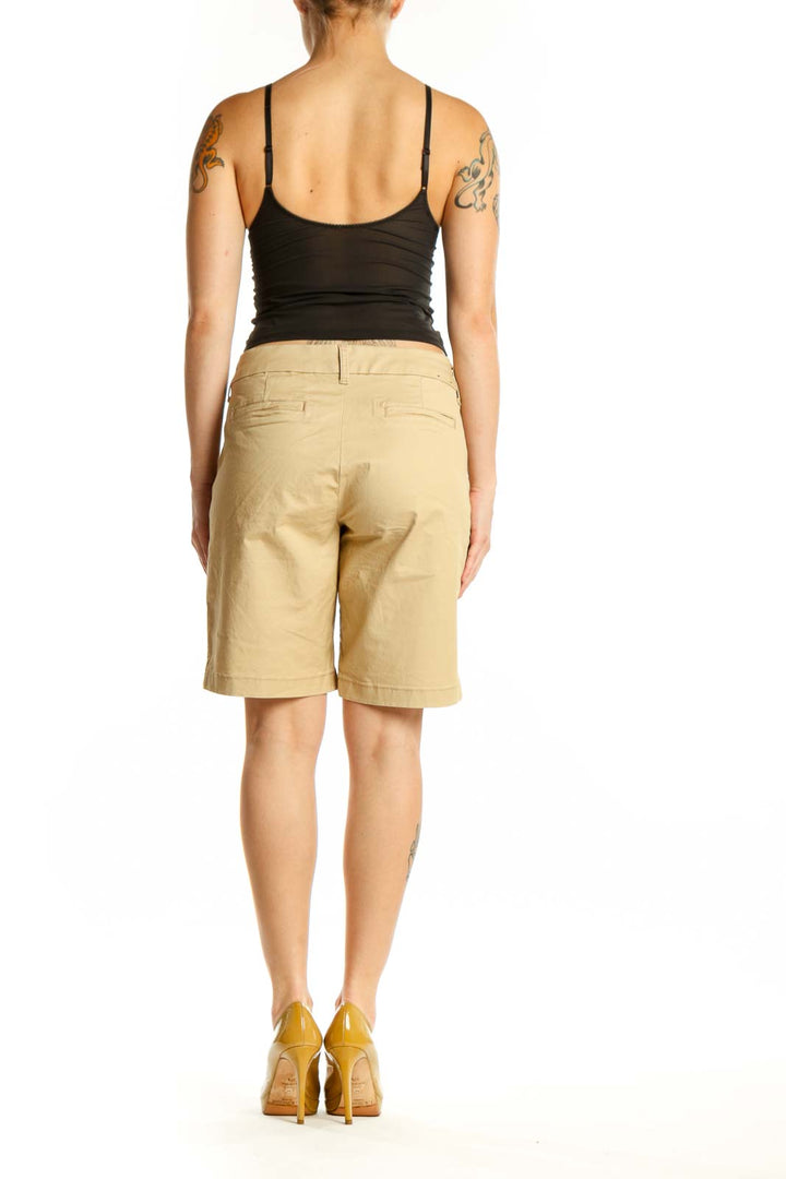 Back view of beige cotton Bermuda shorts showing rear pockets and knee-length cut