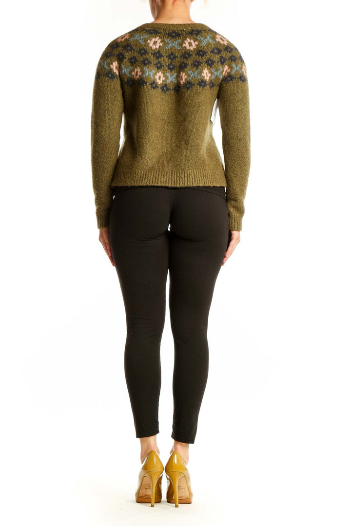Back view of olive Fair Isle cardigan showing patterned shoulders and cropped length, styled with black pants and gold heels
