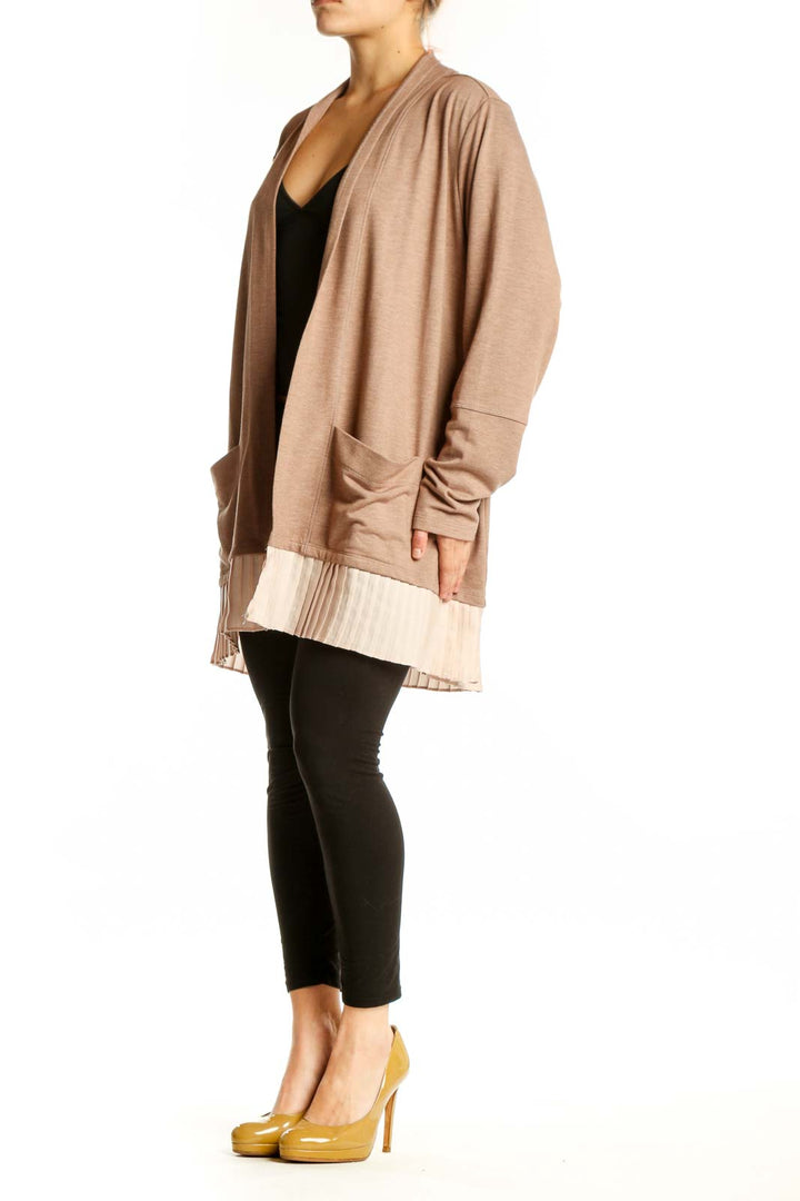 Beige open-front cardigan with pleated cream hem worn over black top, front view