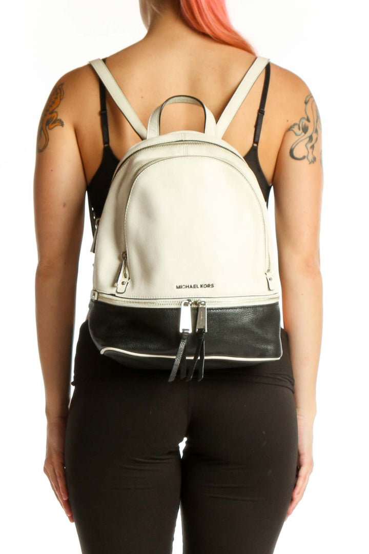 Cream and black Michael Kors leather backpack with dual-zipper closure and padded handles, front view