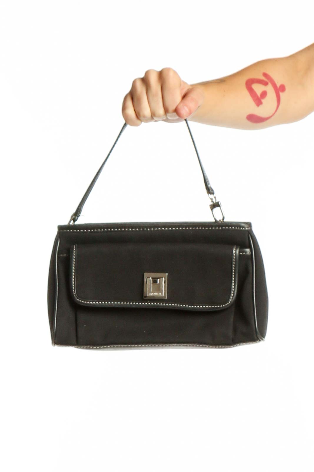 Black studded clutch with metal studs and turnlock closure held by hand, showing front view