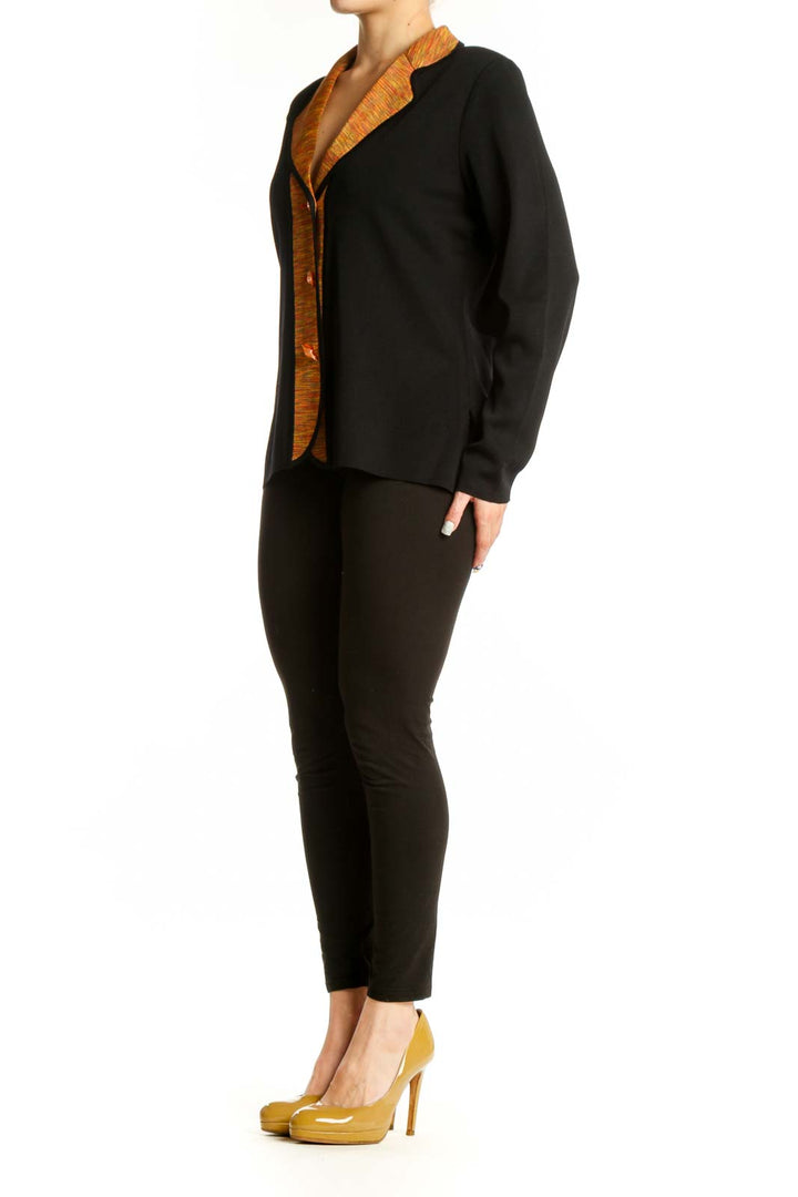 Black acrylic cardigan with orange textured trim and button-front closure, worn on model