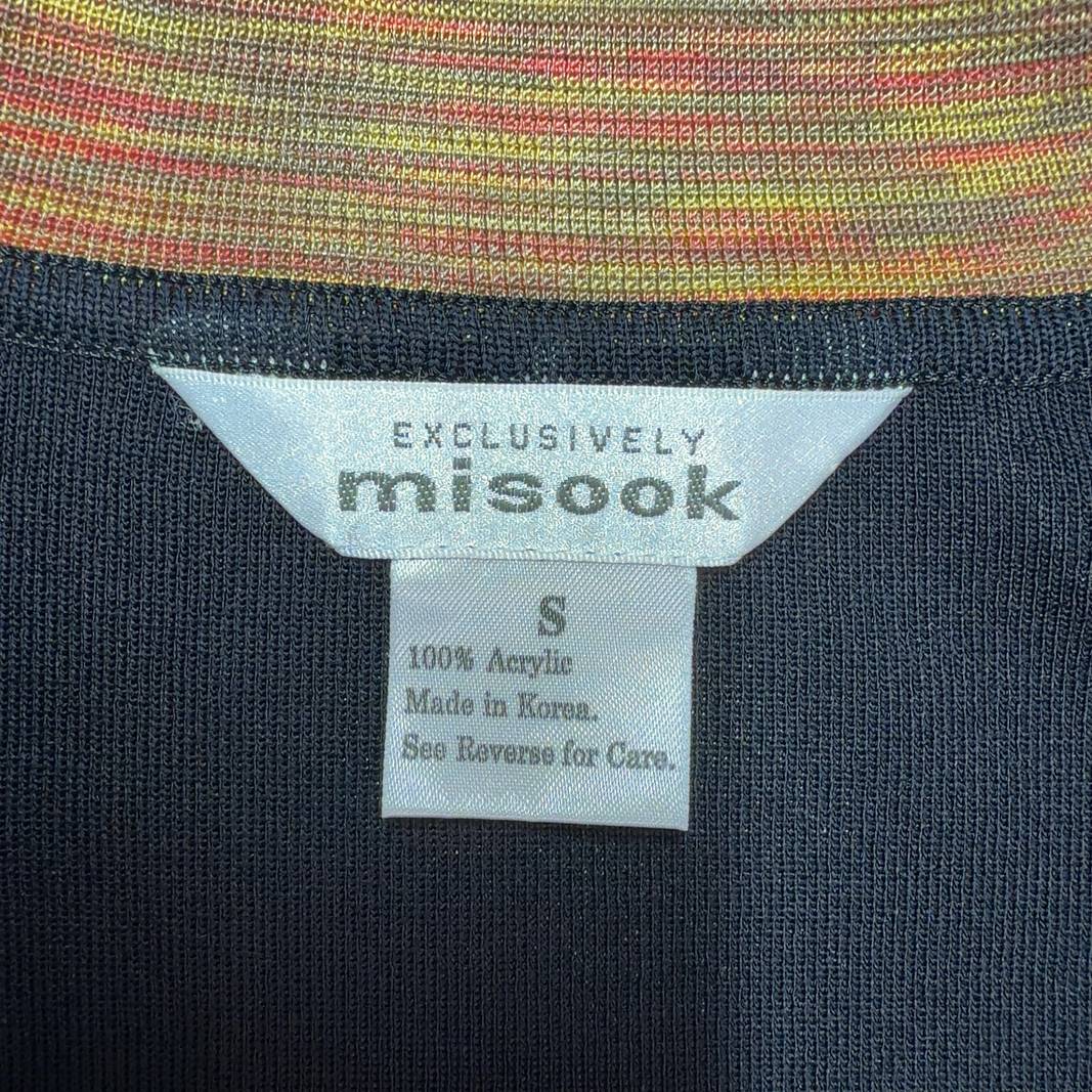 Tag view of black cardigan with orange trim detail, showing structured silhouette and long sleeves