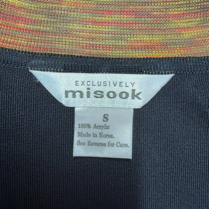 Tag view of black cardigan with orange trim detail, showing structured silhouette and long sleeves