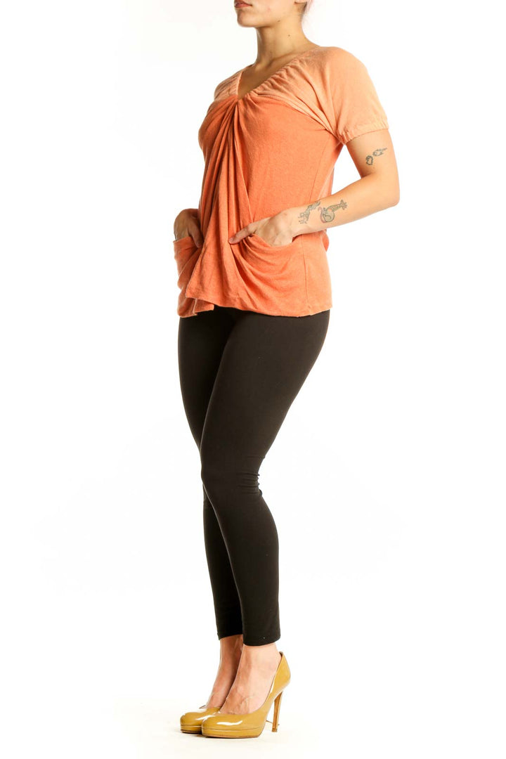 Free People orange ruched cotton-linen top with V-neckline and puffed sleeves, front view on model