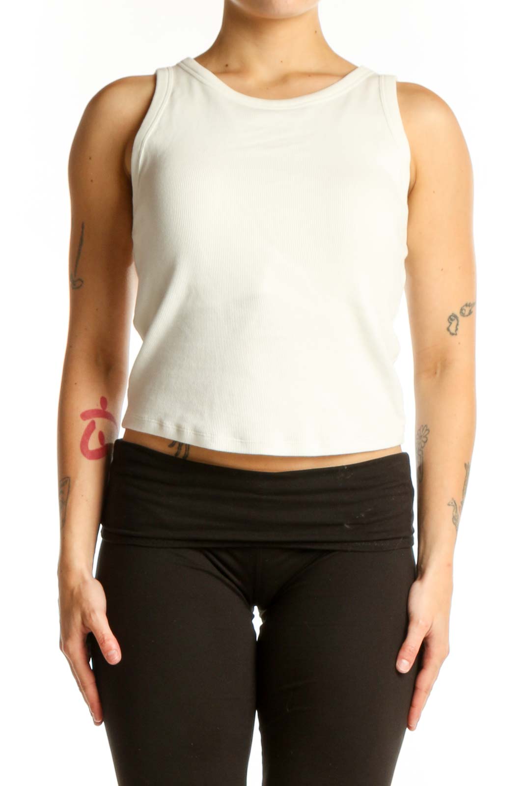 Cream ribbed sleeveless tank top worn with black leggings, front view