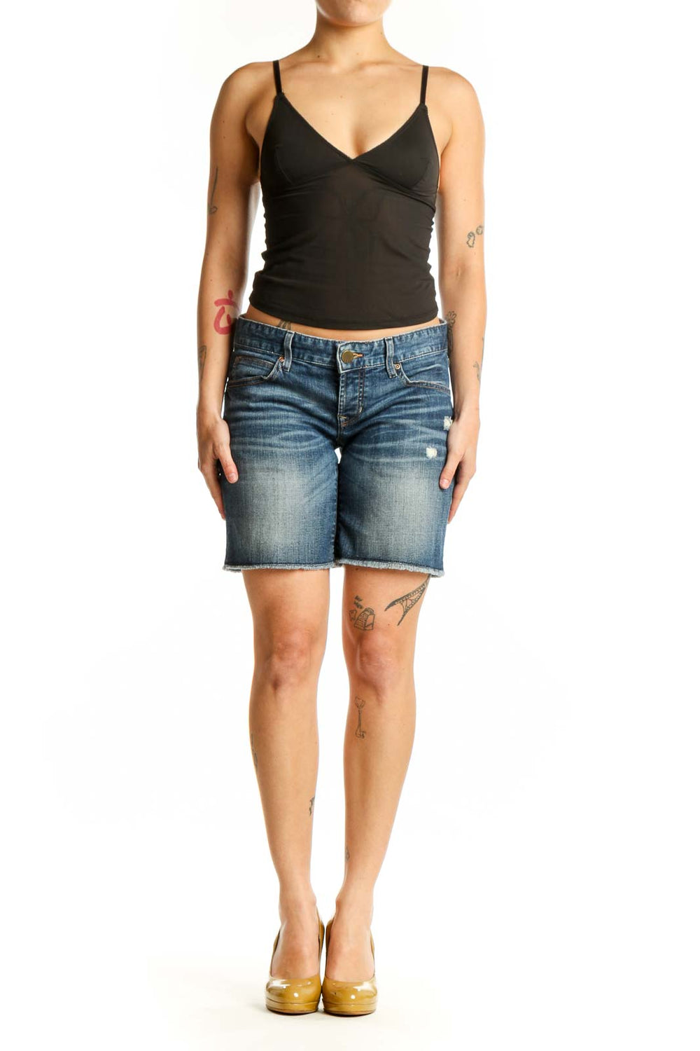 Blue denim distressed shorts front view, medium wash with ripped details, worn with black crop top