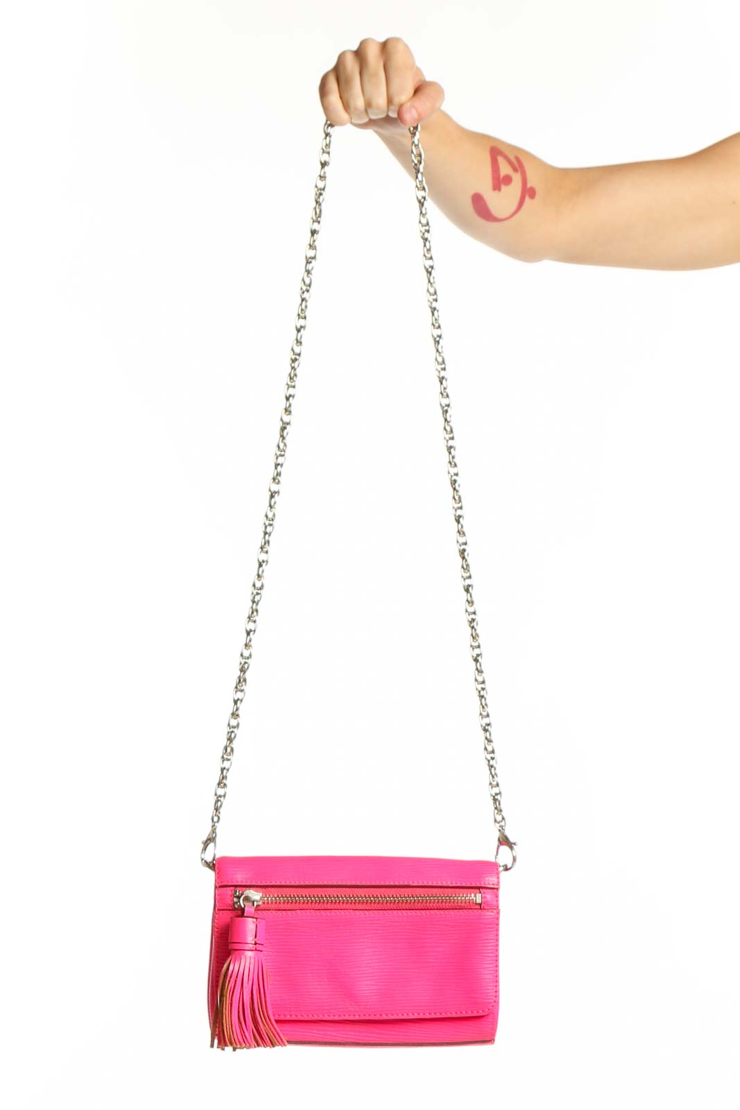 Hot pink Rebecca Minkoff leather crossbody bag with silver chain strap and tassel accent, held by hand