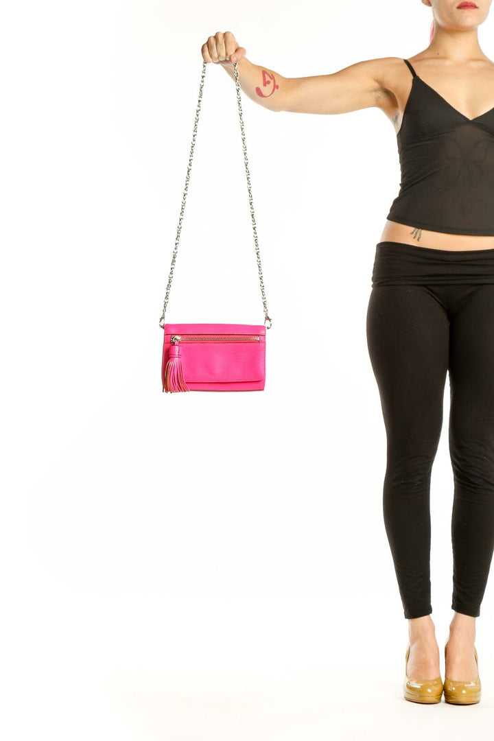 Hot pink Rebecca Minkoff leather crossbody bag with silver chain strap and tassel accent, held by hand
